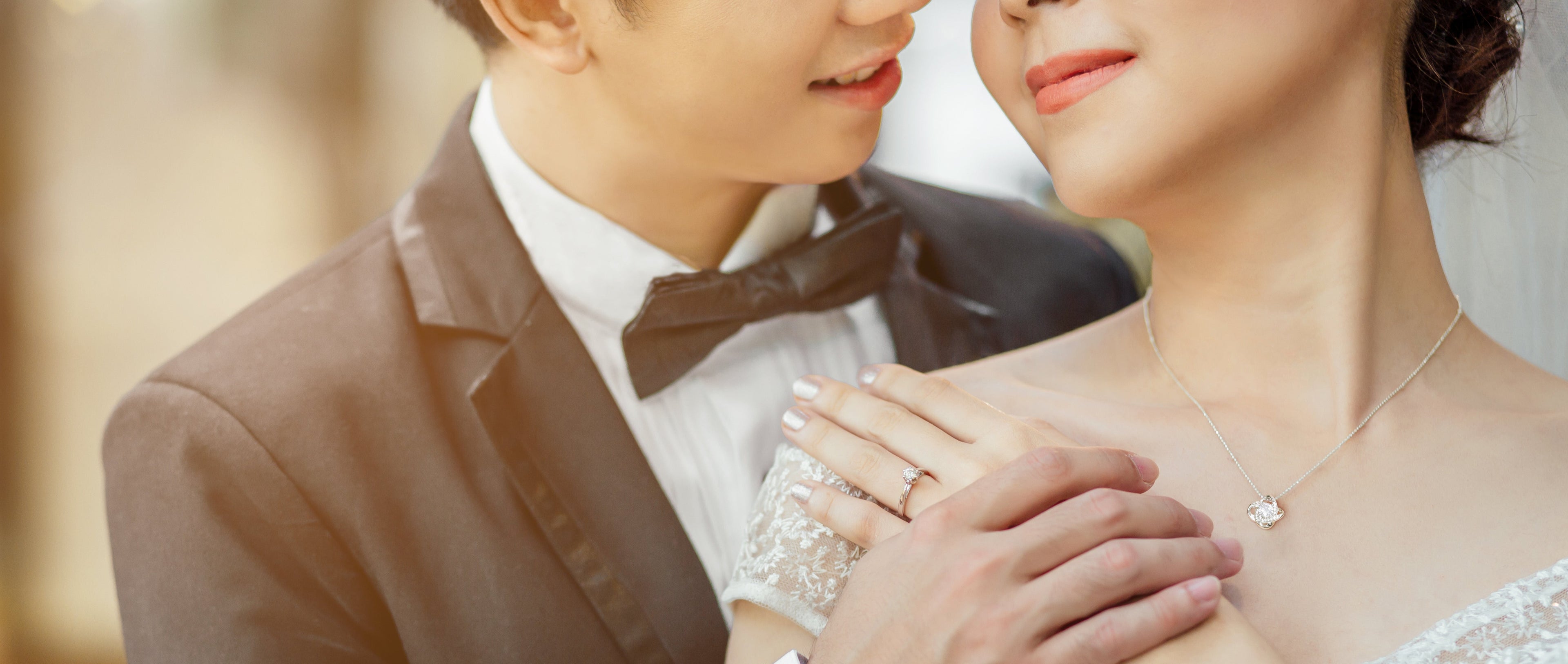 Couple in formal attire with a focus on their hands and love knot necklace